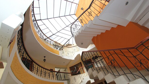 A multi-level interior with a spiral staircase, a glass ceiling, and a yellow accent wall. - Hotel De La Villa Hermoza (Cusco)