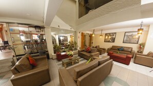 A spacious living area with multiple sofas, a coffee table, and a dining area with chairs and a table. - Hotel De La Villa Hermoza (Cusco)