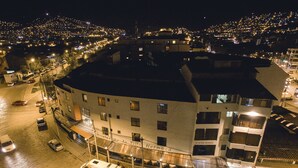 A hotel with multiple floors, a parking area, and a street view at night. - Hotel De La Villa Hermoza (Cusco)