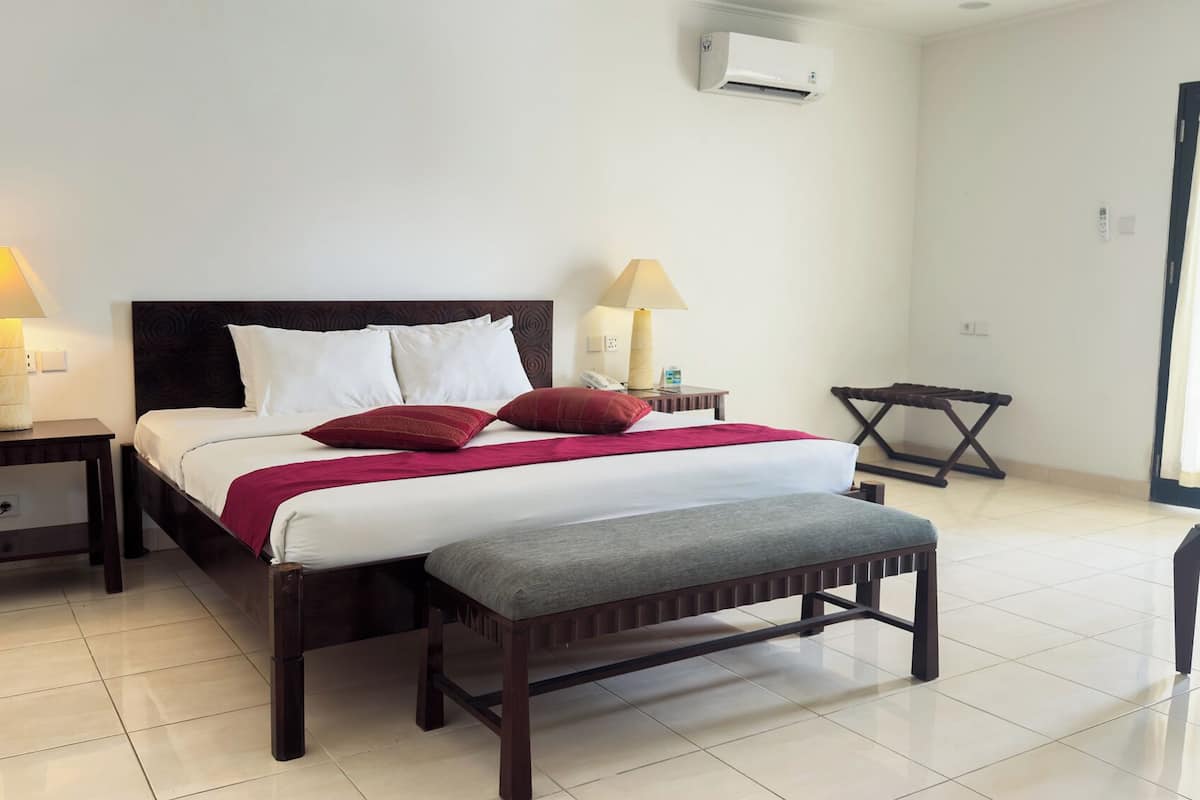 A neatly arranged hotel room with a bed, bedside lamps, a bench, and a small table.