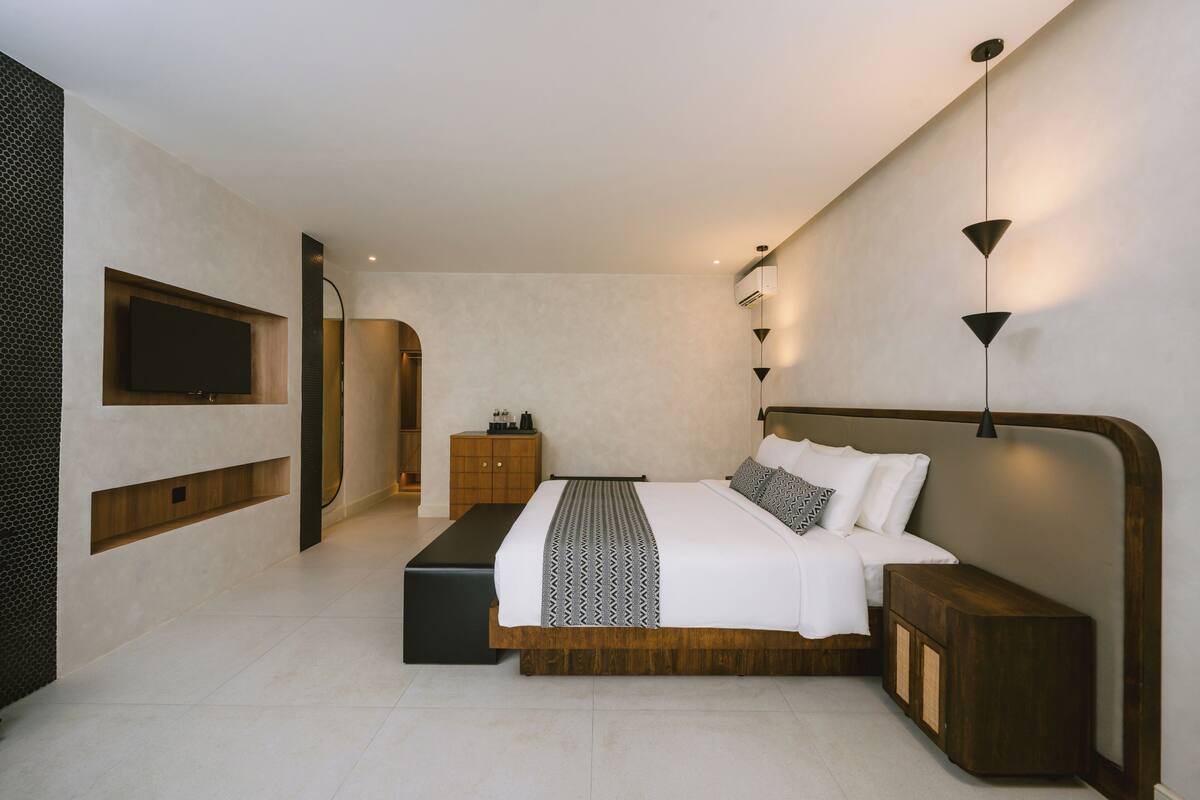 A modern bedroom with a large bed, a TV mounted on the wall, and a bedside table.