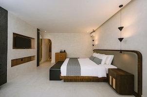 Un dormitorio moderno con una cama grande, un televisor instalado en la pared y una mesita de noche.