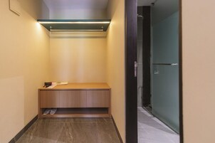 Un pasillo estrecho con un banco, una puerta que da al baño y un suelo de baldosas.