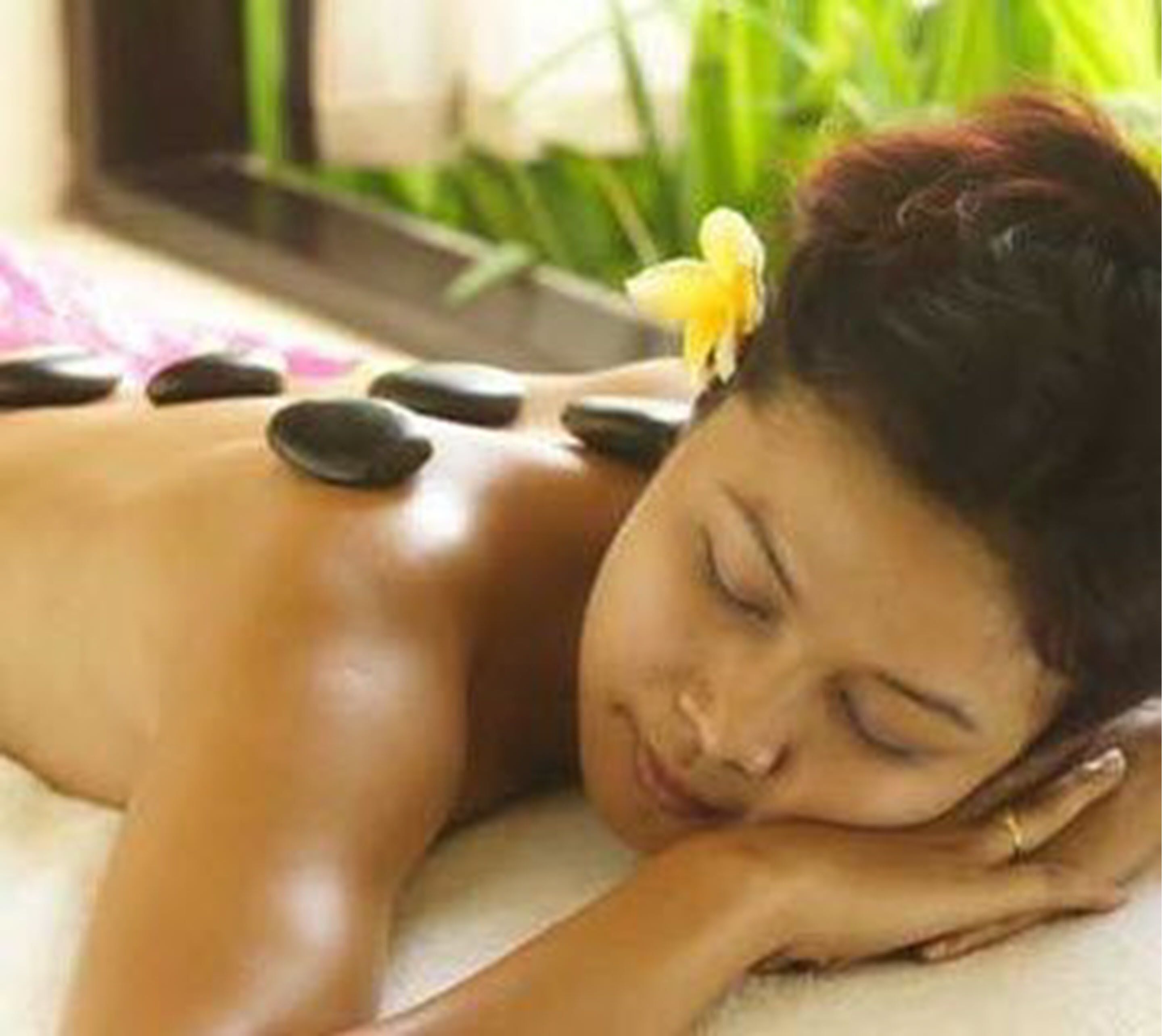 A person receiving a hot stone massage with stones placed on their back.