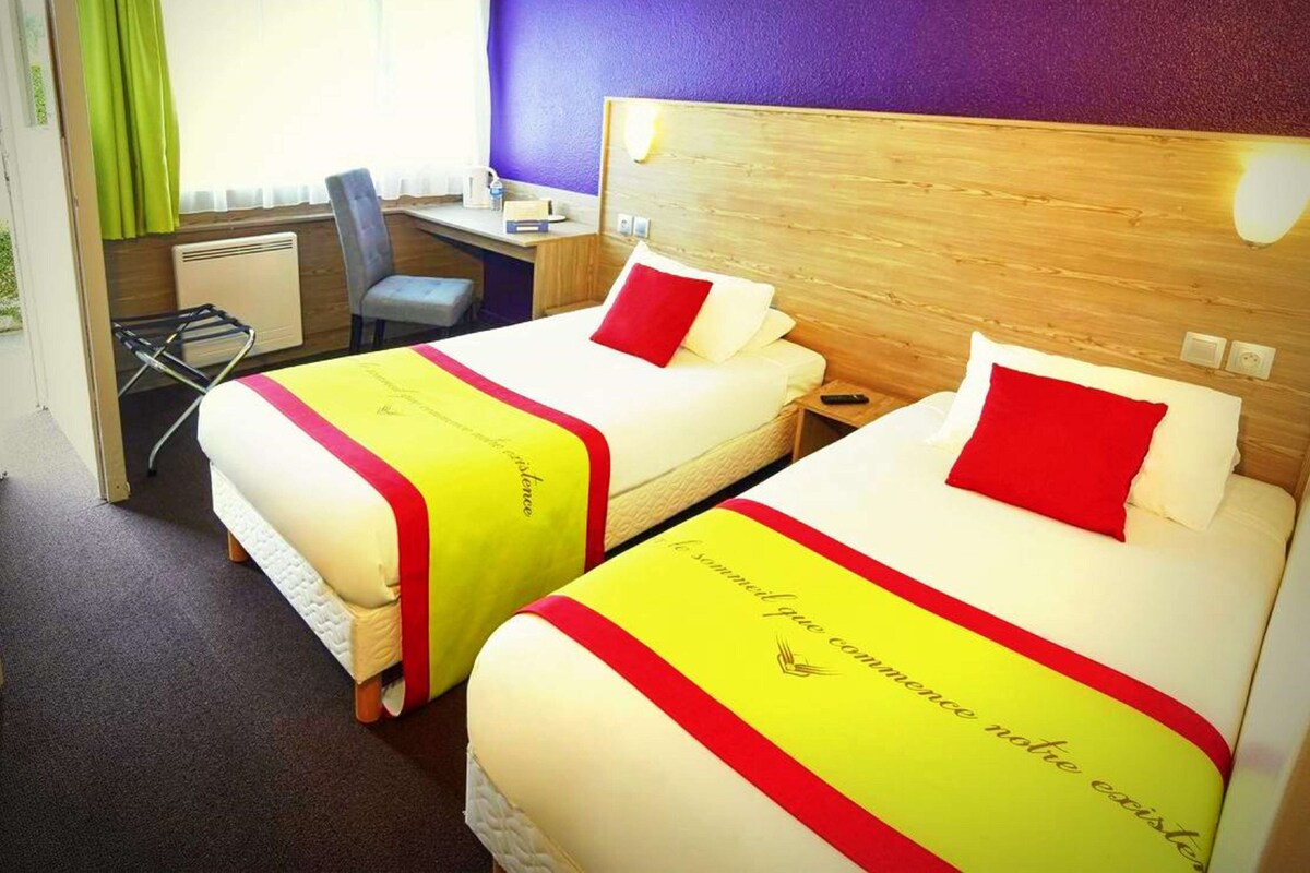 Habitación de hotel con dos camas, un escritorio y una silla.