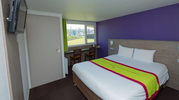 Een hotelkamer met een bed, een bureau, stoelen en een televisie.