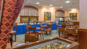 Un comedor con mesas y sillas azules, un acuario decorativo y obras de arte en las paredes.
