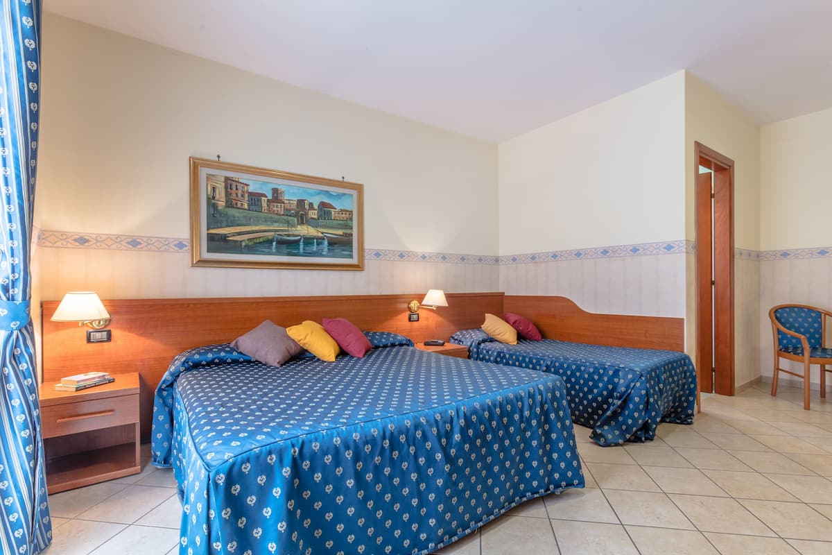 A hotel room with two beds, a nightstand, a chair, and a painting on the wall.