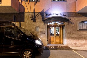 A black car parked in front of Hotel Traiano, with a wooden entrance and a sign above the door. - Hotel Traiano (Civitavecchia)