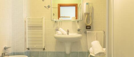 A bathroom with a sink, bidet, and towel rack.