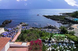 A coastal resort with a pool area, lounge chairs, and a view of the ocean. - Nike Hotel (Giardini Naxos)