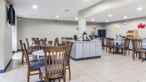 Un comedor amplio con varias mesas y sillas, una isla central con pileta y un televisor de pantalla plana montado en la pared.