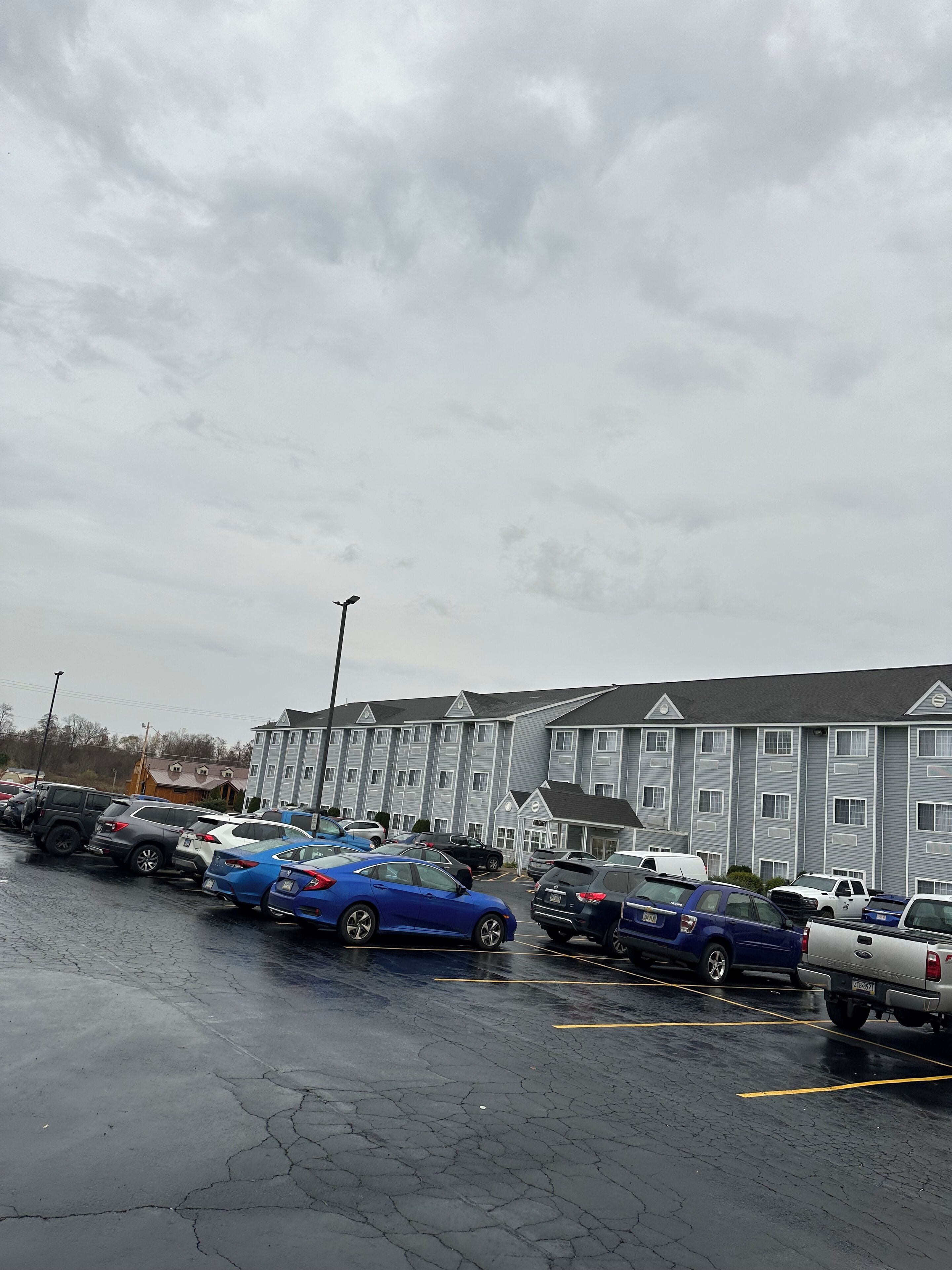 A parking lot with several cars and a multi-story building in the background.