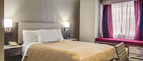 Une chambre d’hôtel avec un grand lit, des lampes de chevet, un bureau et une fenêtre avec des rideaux.