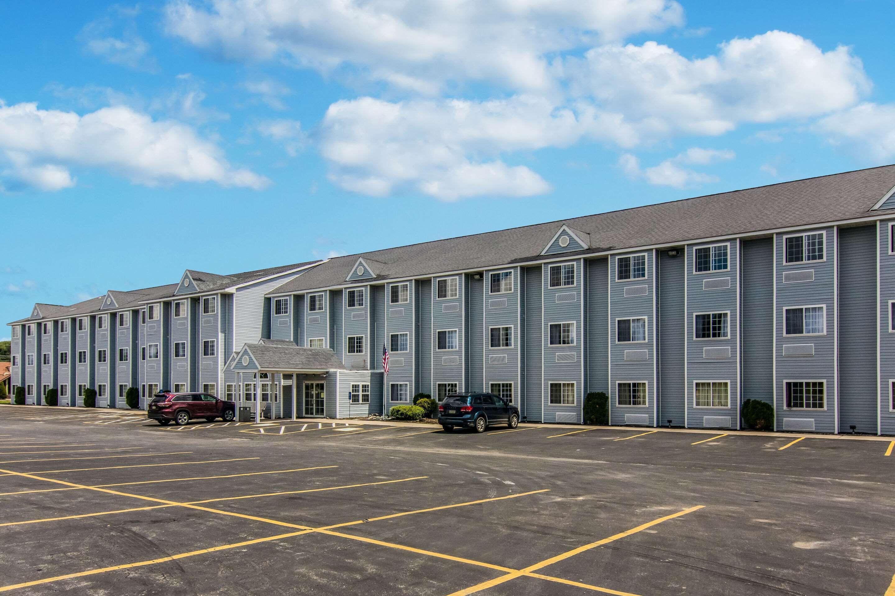 A multi-story hotel with a parking lot in front.