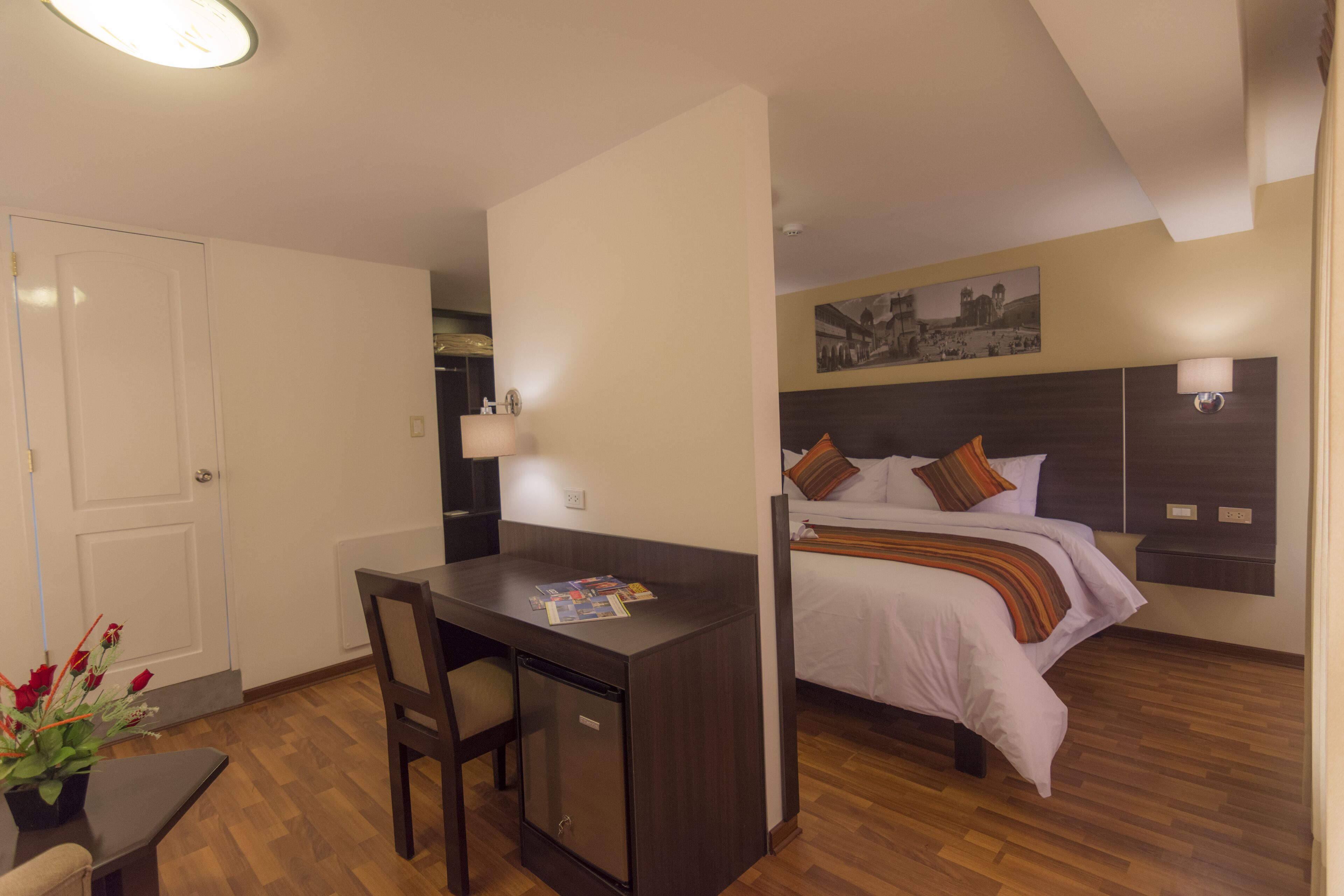 A compact hotel room with a bed, a desk, and a chair.