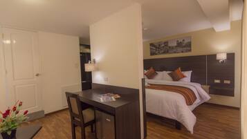A compact hotel room with a bed, a desk, and a chair.