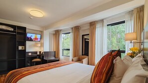 Ein Hotelzimmer mit einem großen Bett, einem Schreibtisch, einem Fernseher und einem Kleiderschrank.