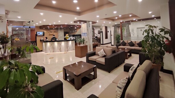 Eine Hotelhalle mit Empfangstresen, Sofas, einem Couchtisch und Topfpflanzen.