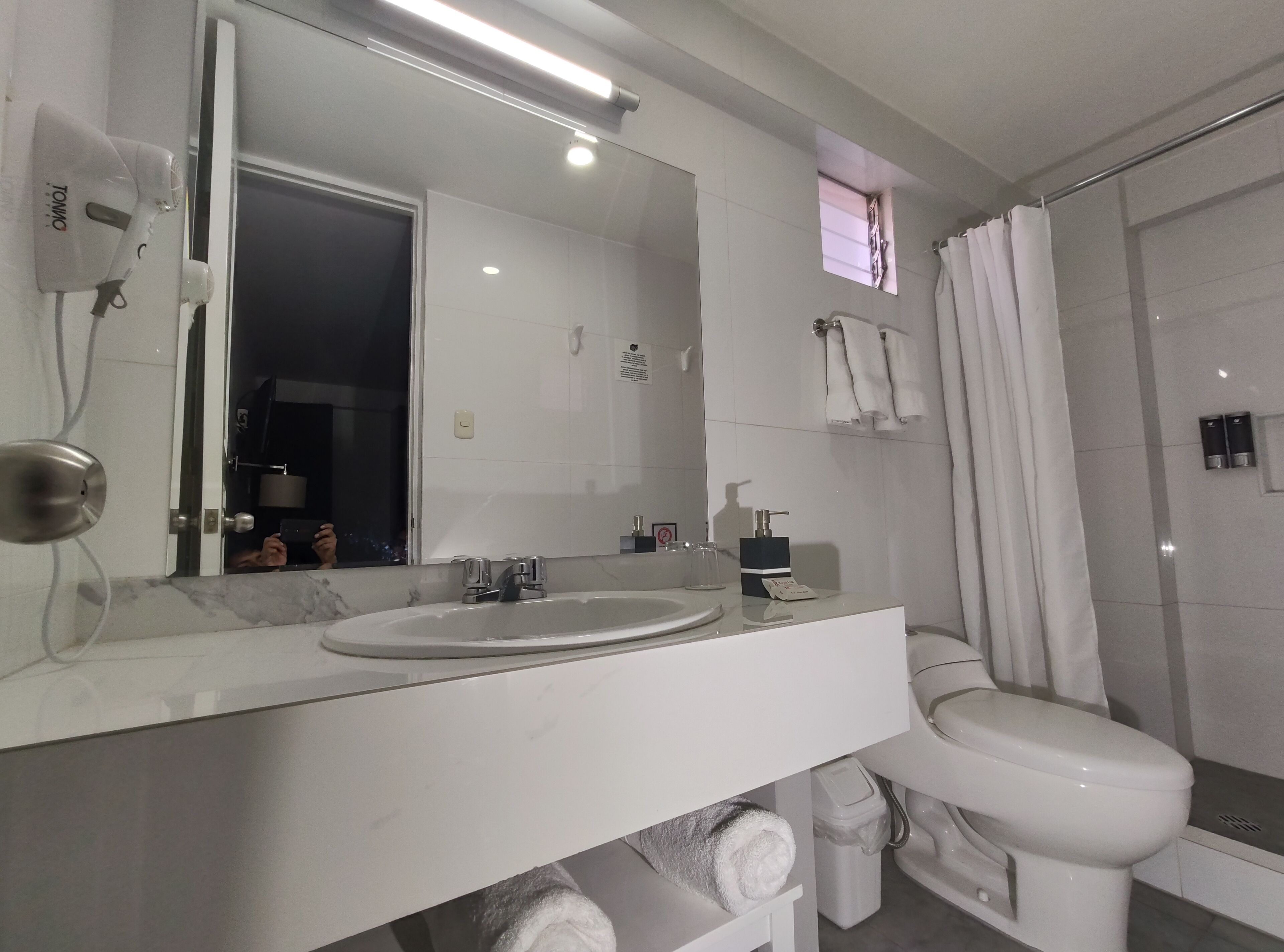 A modern bathroom with a large mirror, a sink, a toilet, and a shower area.