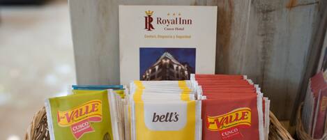 A basket of Valle Mate de Coca and Manzanilla coffee packets, a Royal Inn Cusco Hotel sign, and a wicker basket.