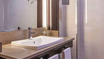 A modern bathroom with a large mirror, a sink, and a shower area.