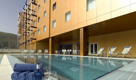 Una piscina al aire libre de temporada, sillones reclinables de piscina