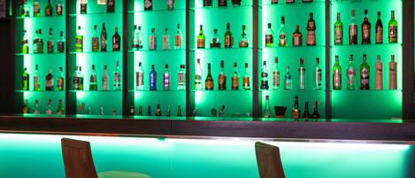 A bar area with multiple shelves of liquor bottles and two wooden chairs.
