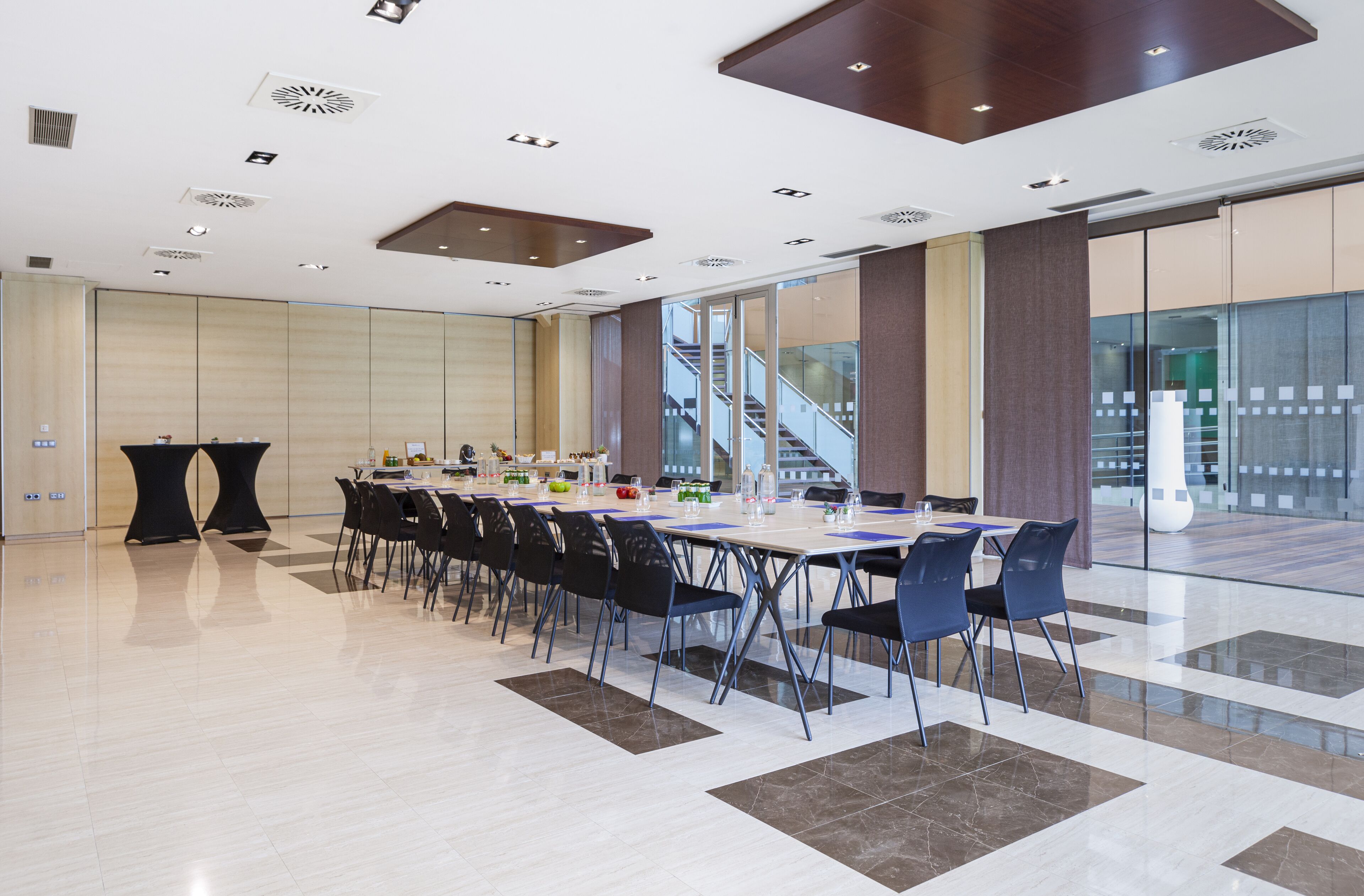 Une salle de conférence moderne, dotée d’une longue table, de chaises et d’une cloison en verre.