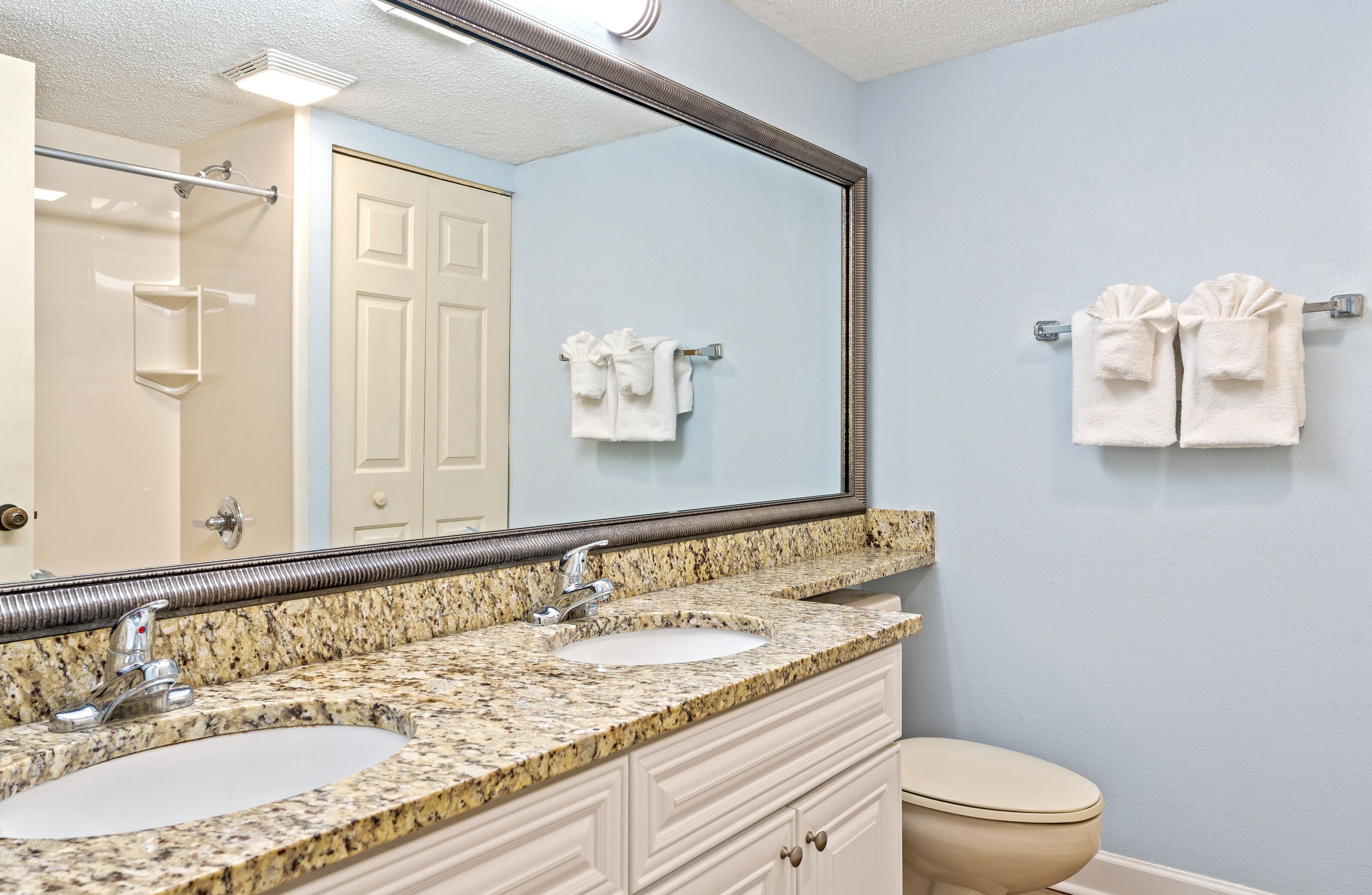 A bathroom with two sinks, a toilet, and a large mirror.