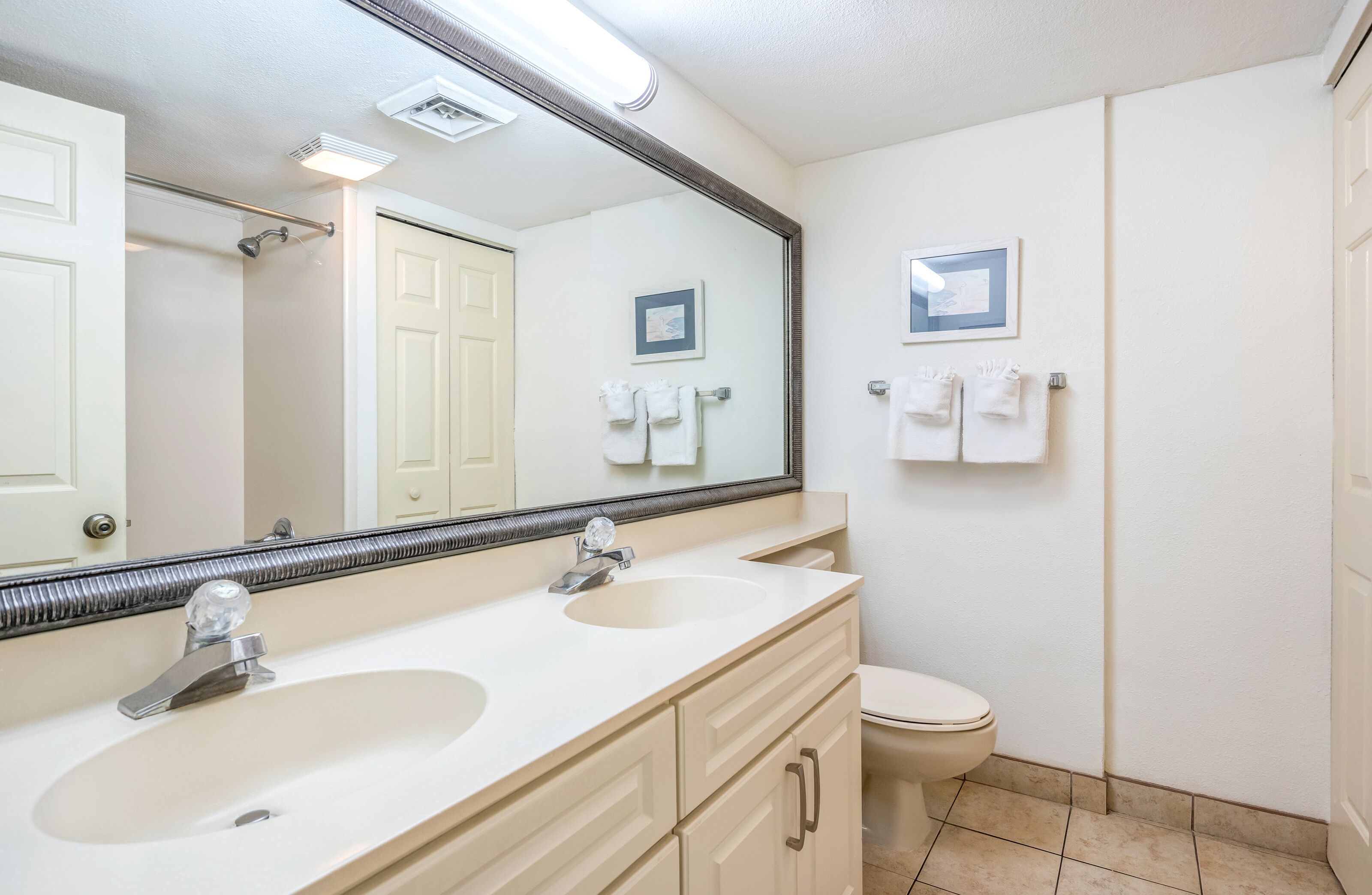 A bathroom with two sinks, a toilet, and a large mirror.