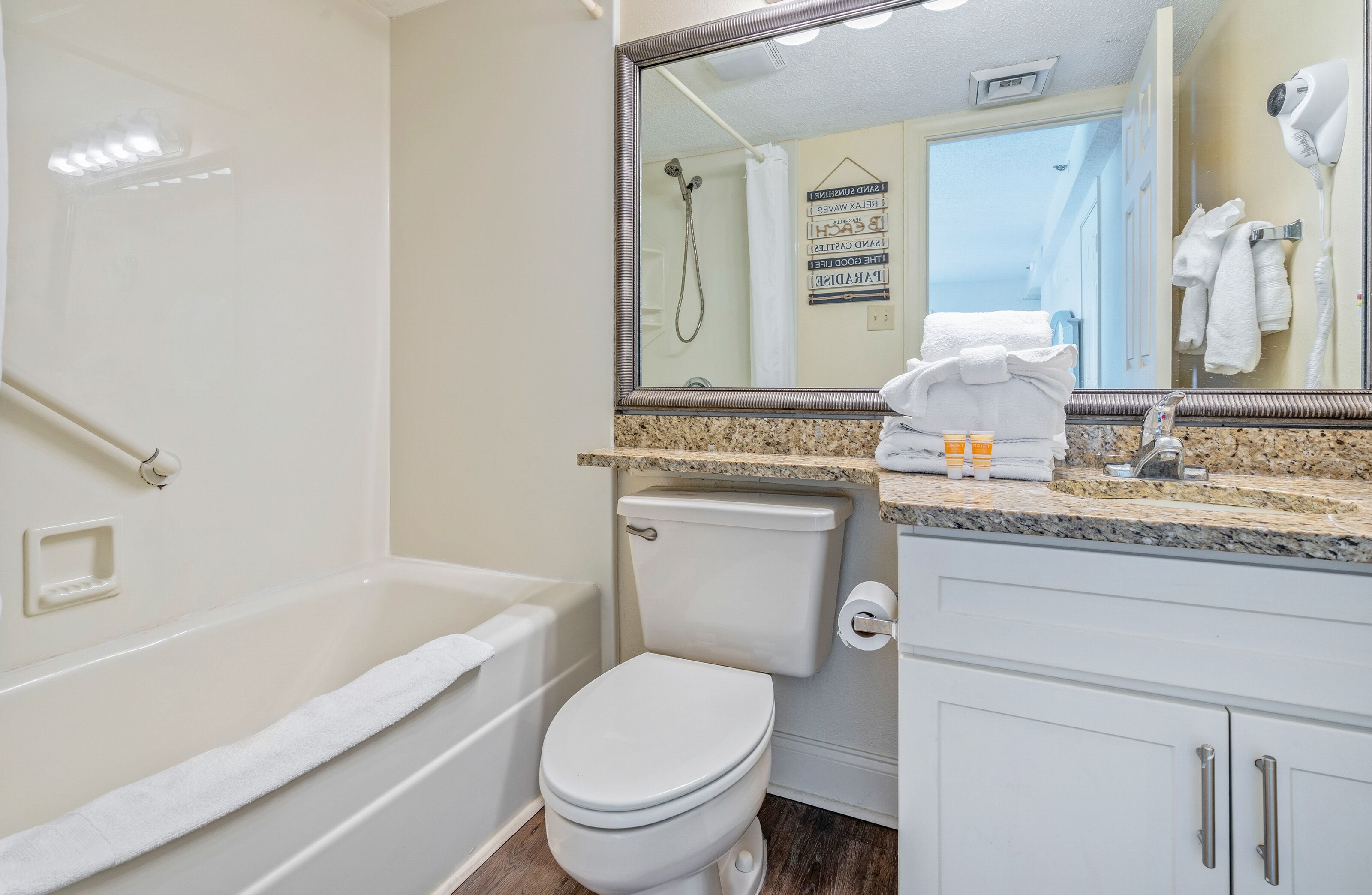 A bathroom with a bathtub, toilet, and a vanity with a mirror.