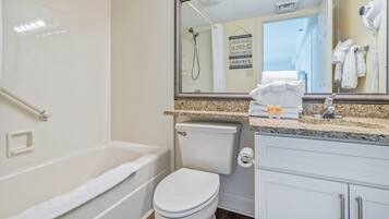 A bathroom with a bathtub, toilet, and a vanity with a mirror.