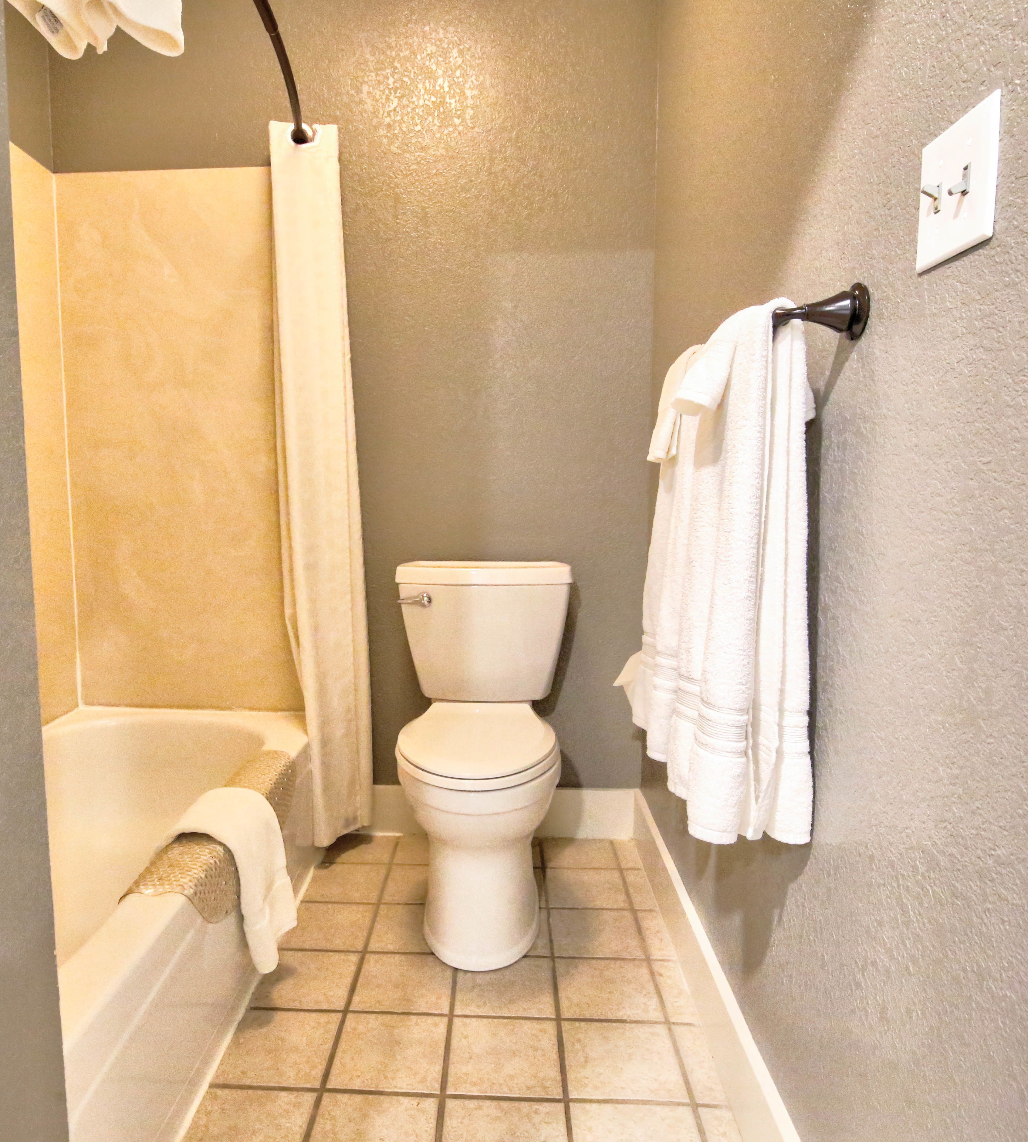 A bathroom with a bathtub, toilet, and a towel rack.