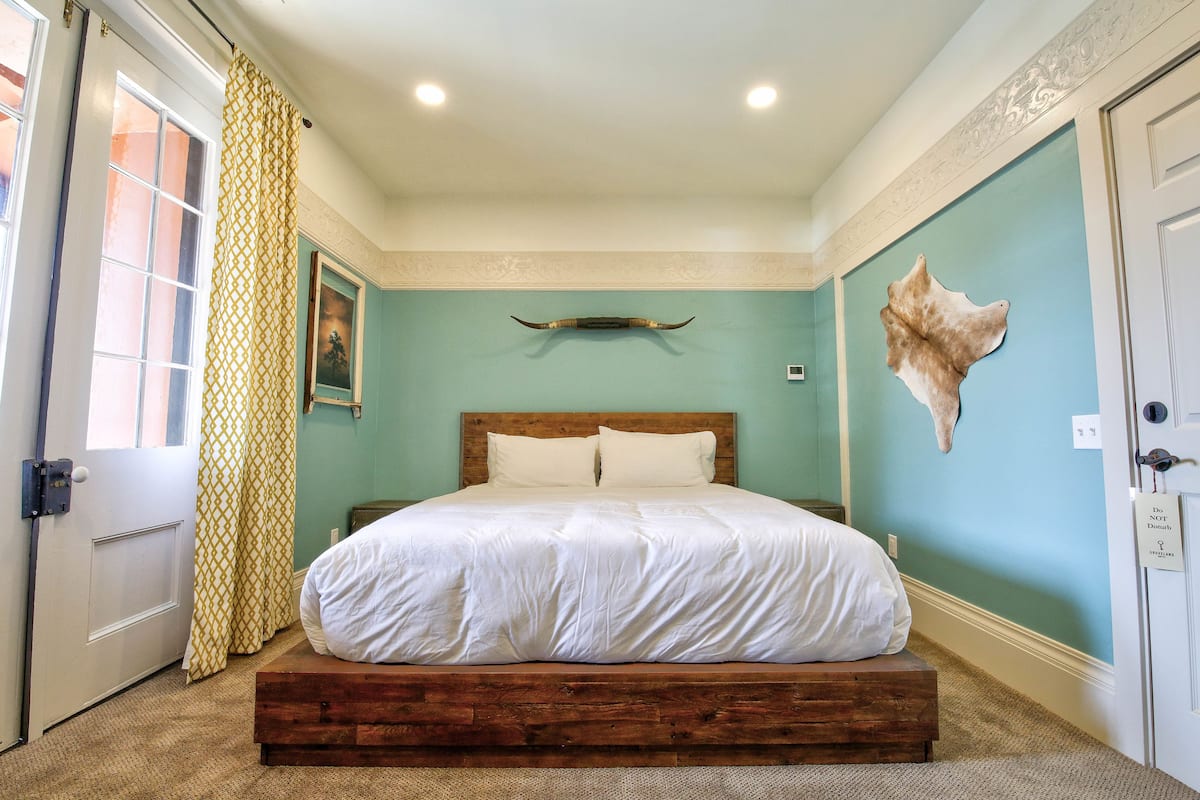Ein Schlafzimmer mit einem hölzernen Bett, einer hellblauen Wand und einem aufgehängten Tierkopf.