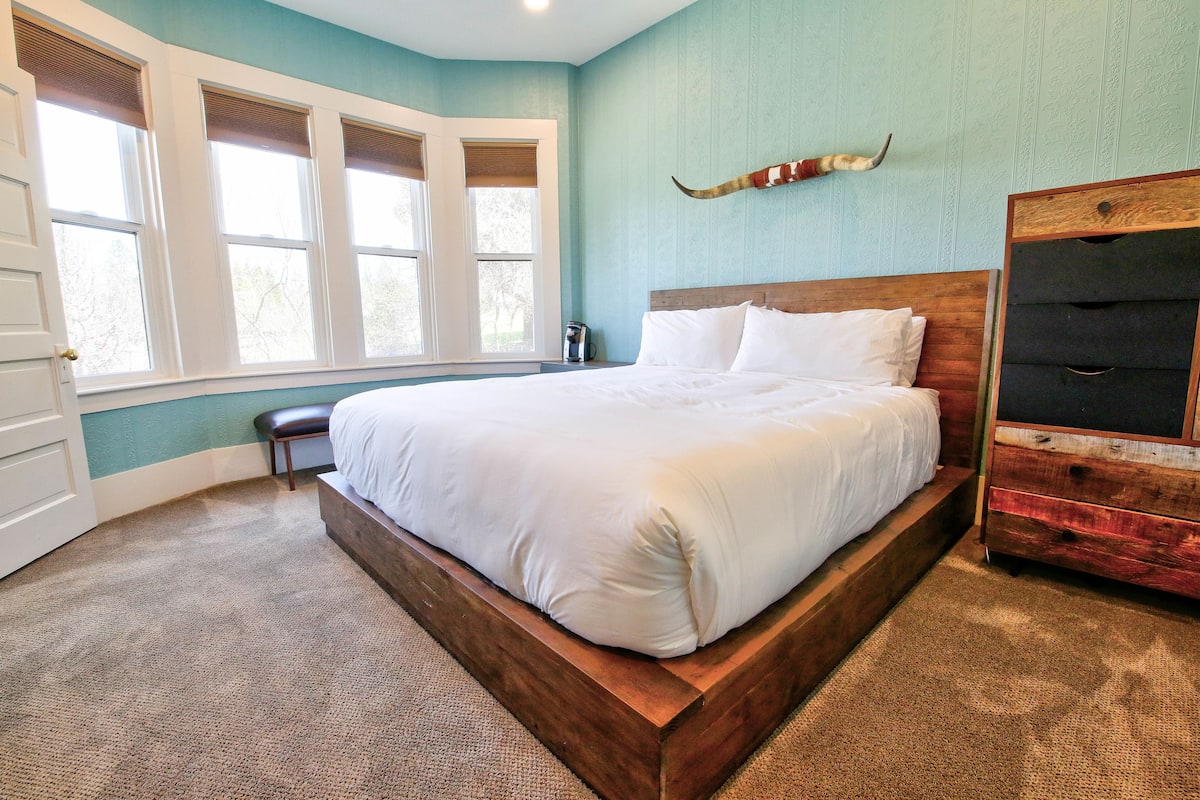 Ein Schlafzimmer mit einem großen Bett, einem Holz-Kopfteil, einer Bank und einem an der Wand montierten Schrank.