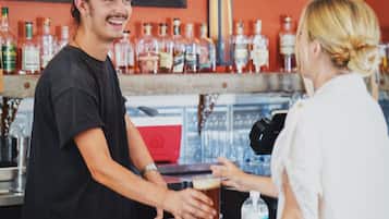 Un bar con un cantinero y un cliente. Se ven varias botellas de licor en la estantería de fondo.