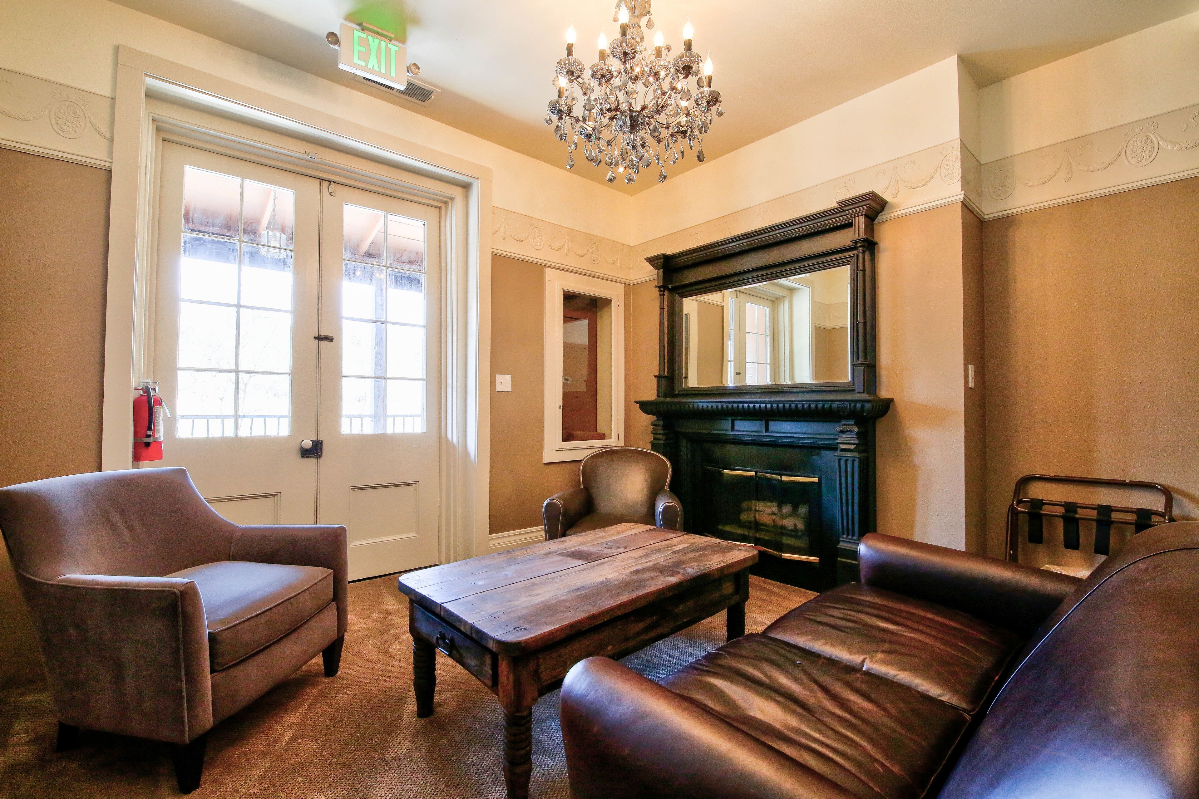 A room with a fireplace, leather sofa, armchair, and a wooden coffee table.