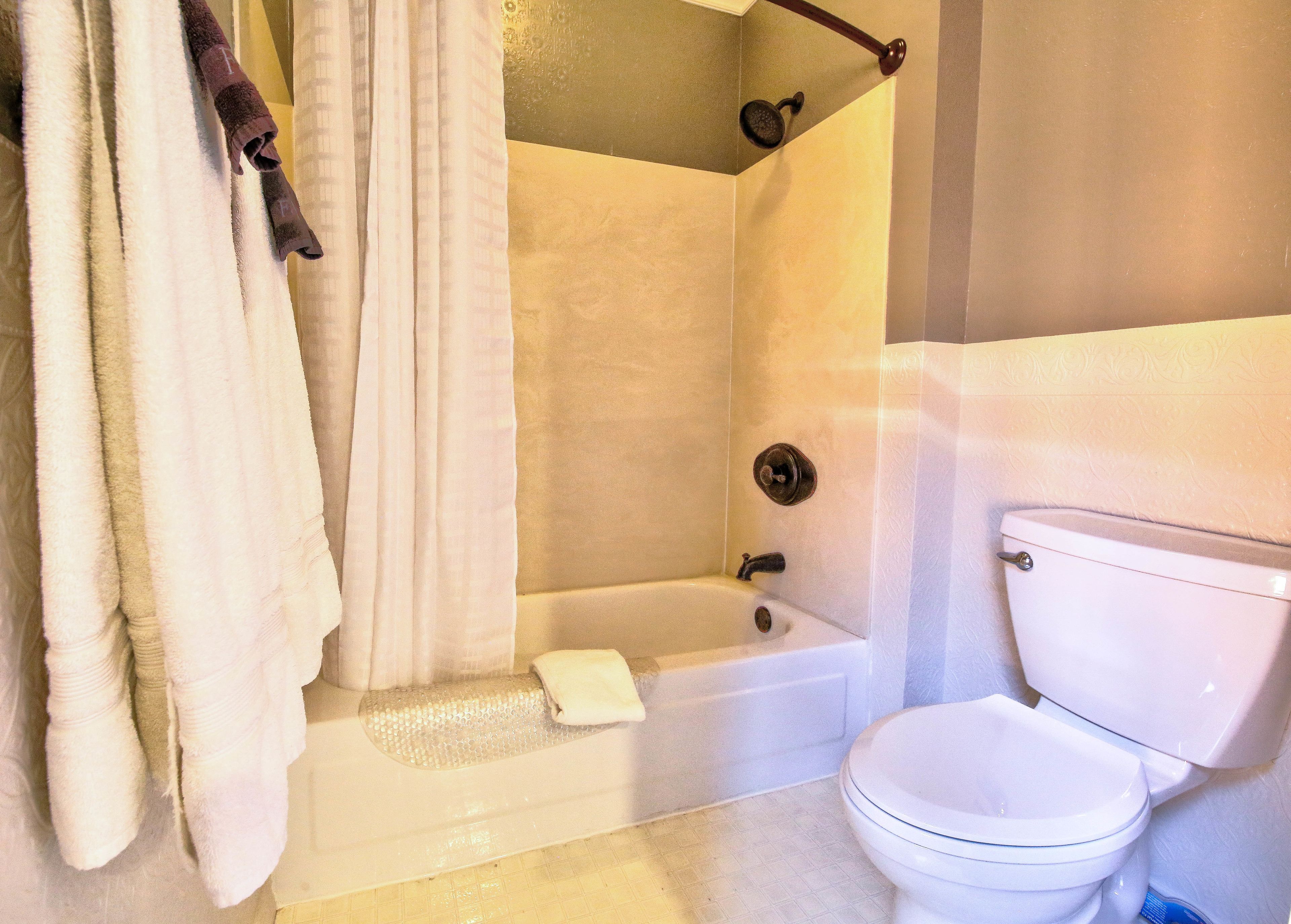 A bathroom with a bathtub, toilet, and shower curtain.