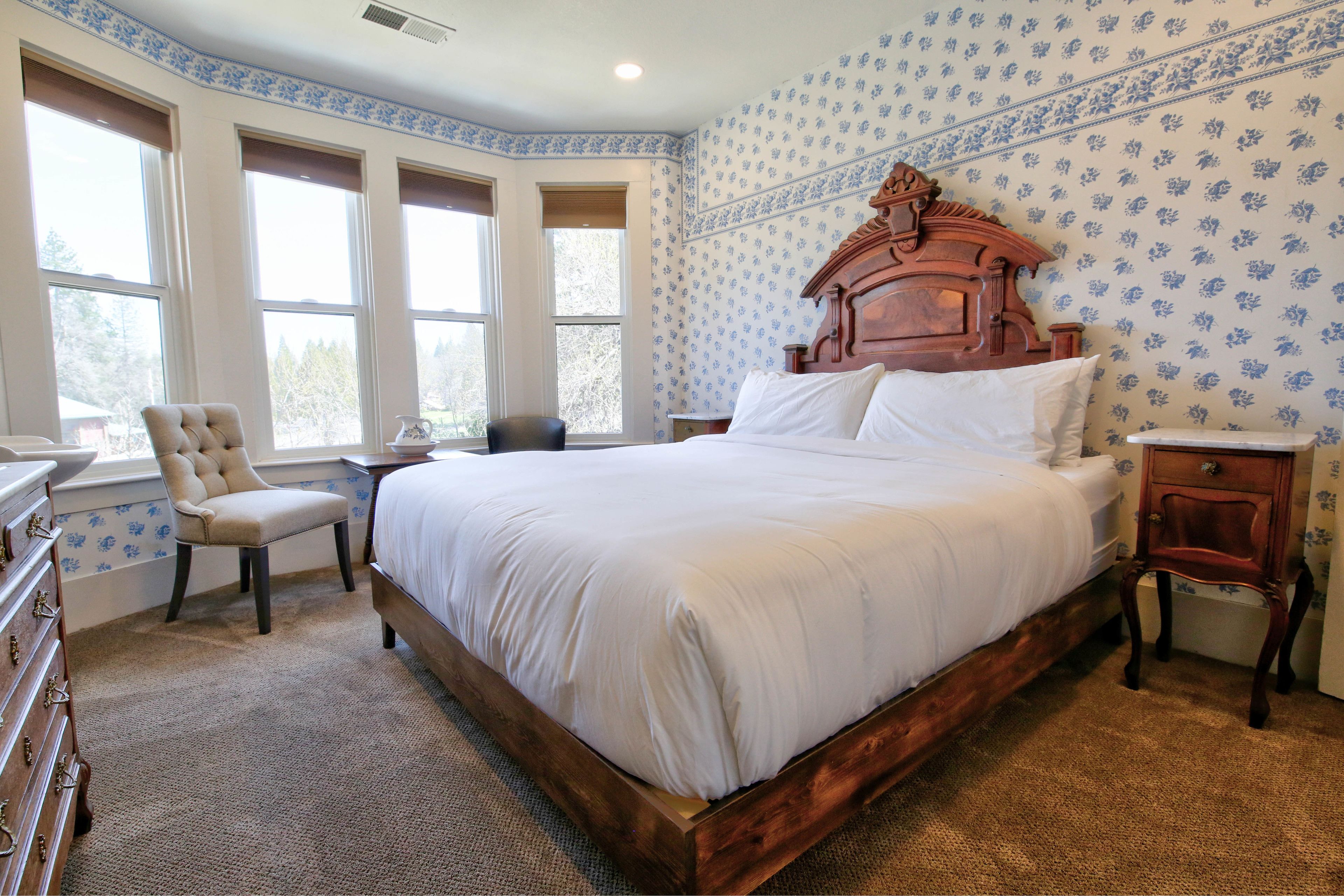A bedroom with a large wooden bed, a chair, a dresser, and a nightstand.