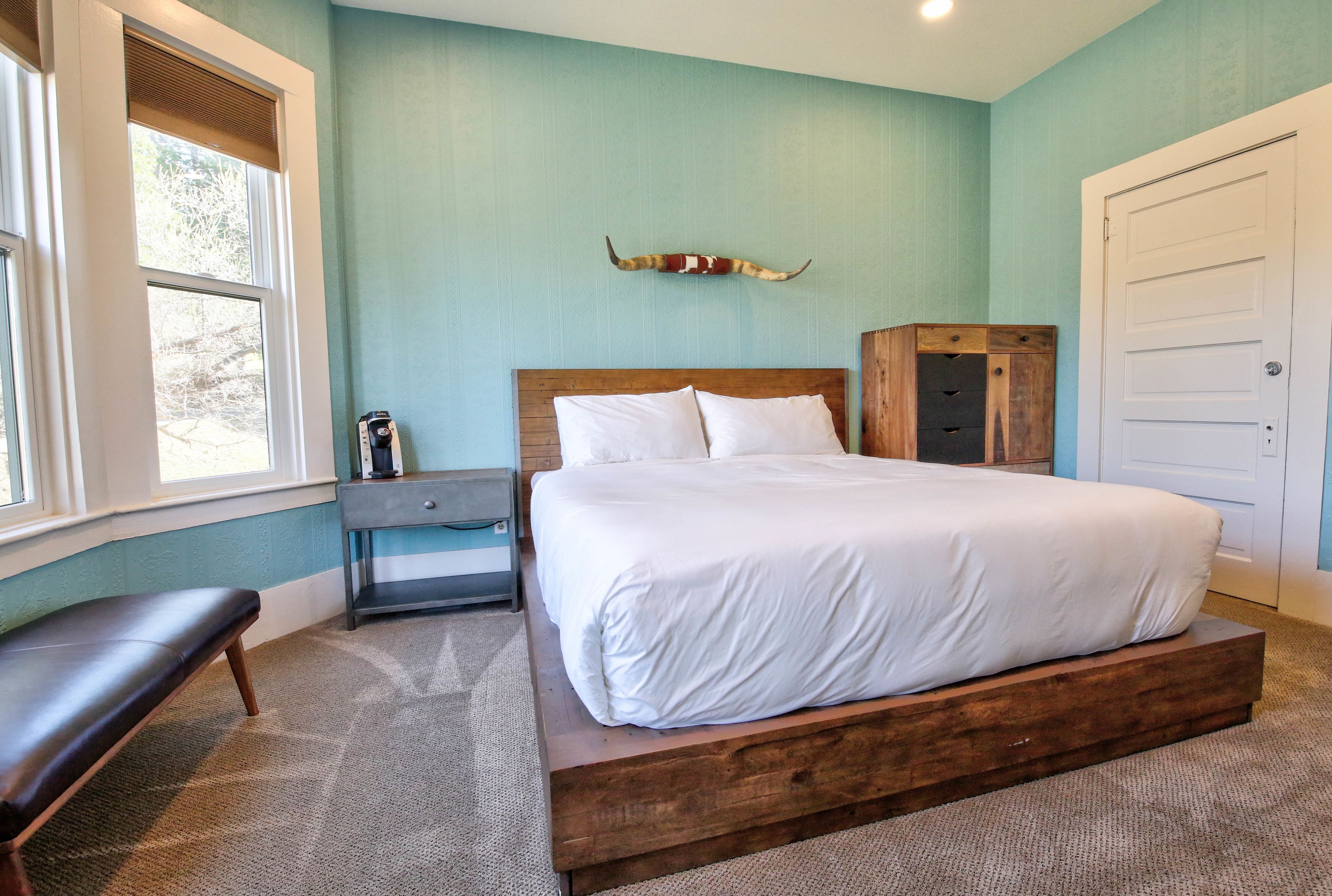 A bedroom with a bed, a bench, a nightstand, a dresser, and a wall-mounted decor piece.