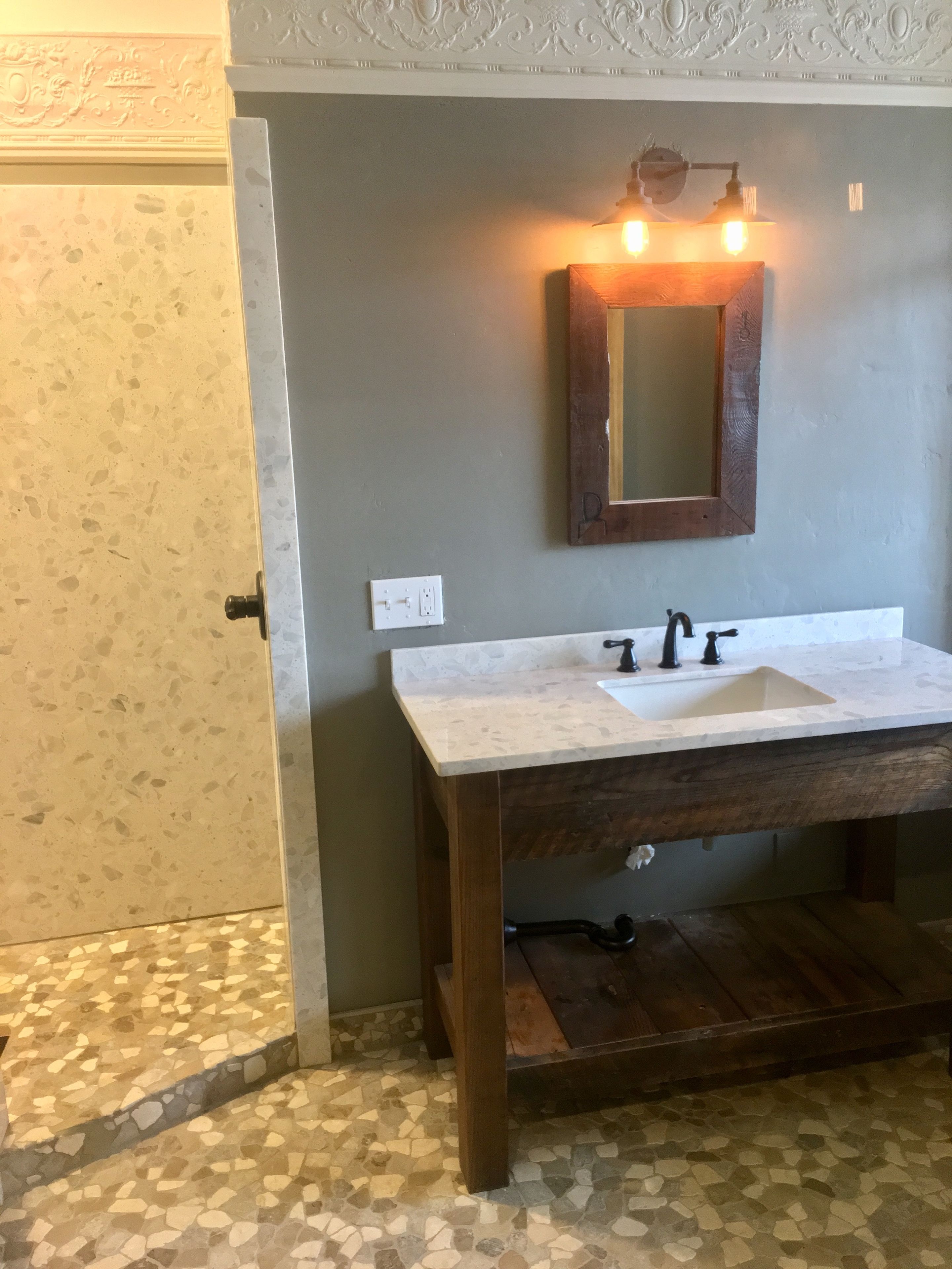 Een badkamer met een witte wasbak, een houten opbergmeubel en een spiegel met verlichting.
