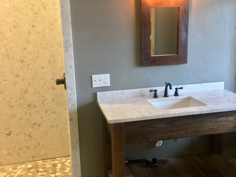 Een badkamer met een witte wasbak, een houten opbergmeubel en een spiegel met verlichting.