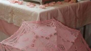 Ein dreistöckiger Kuchen mit rosa Rosen auf der Oberseite, platziert auf einem Tisch mit weißer Spitzenleinentischdecke.