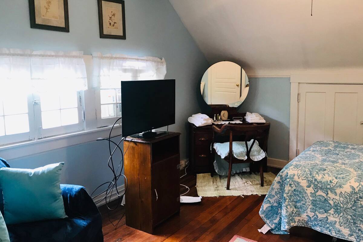 A bedroom with a TV, dresser, mirror, and a bed with a patterned cover.