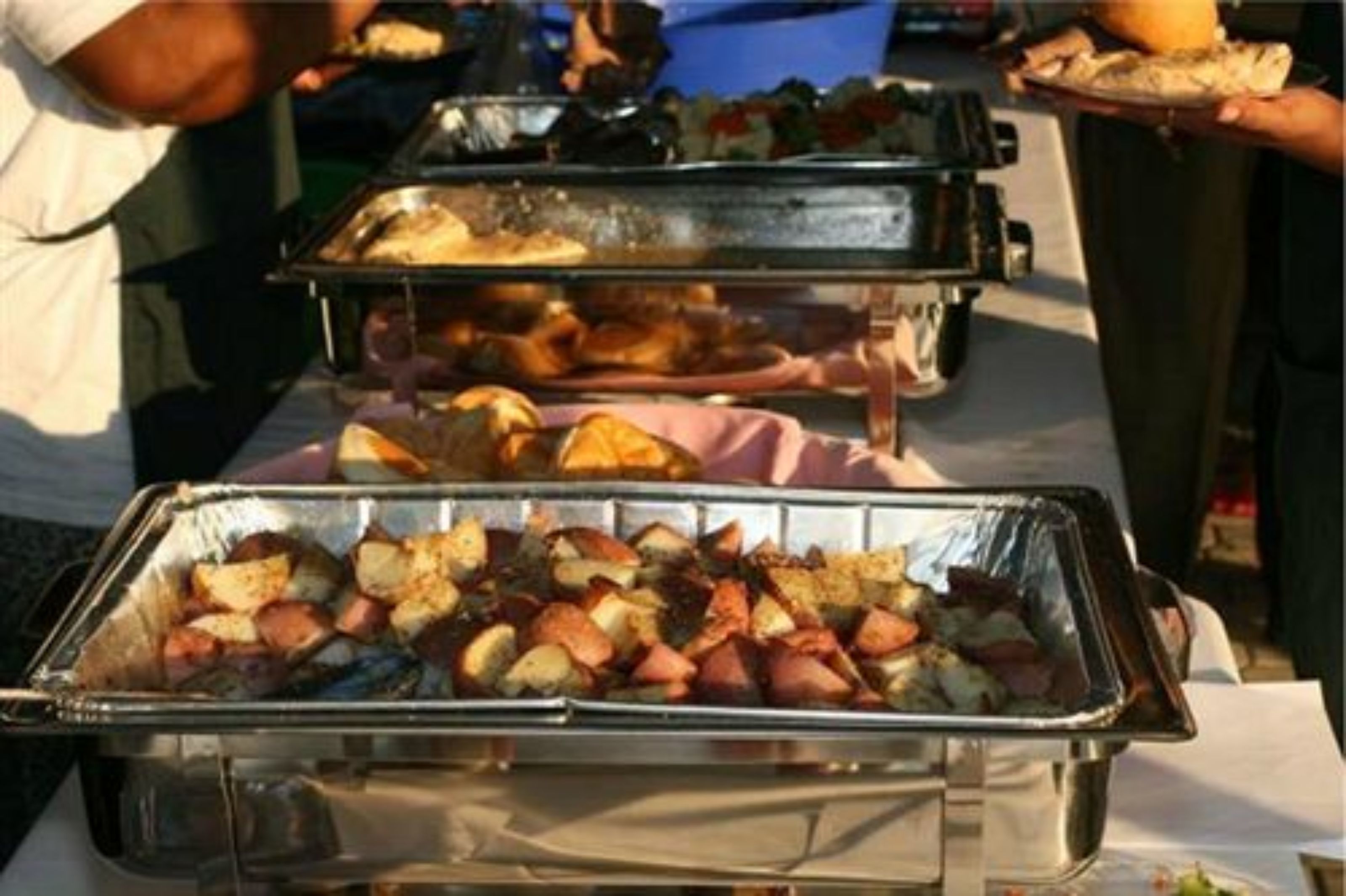 Un buffet proposant une variété de plats, notamment des pommes de terre rôties et différentes sortes de viandes.