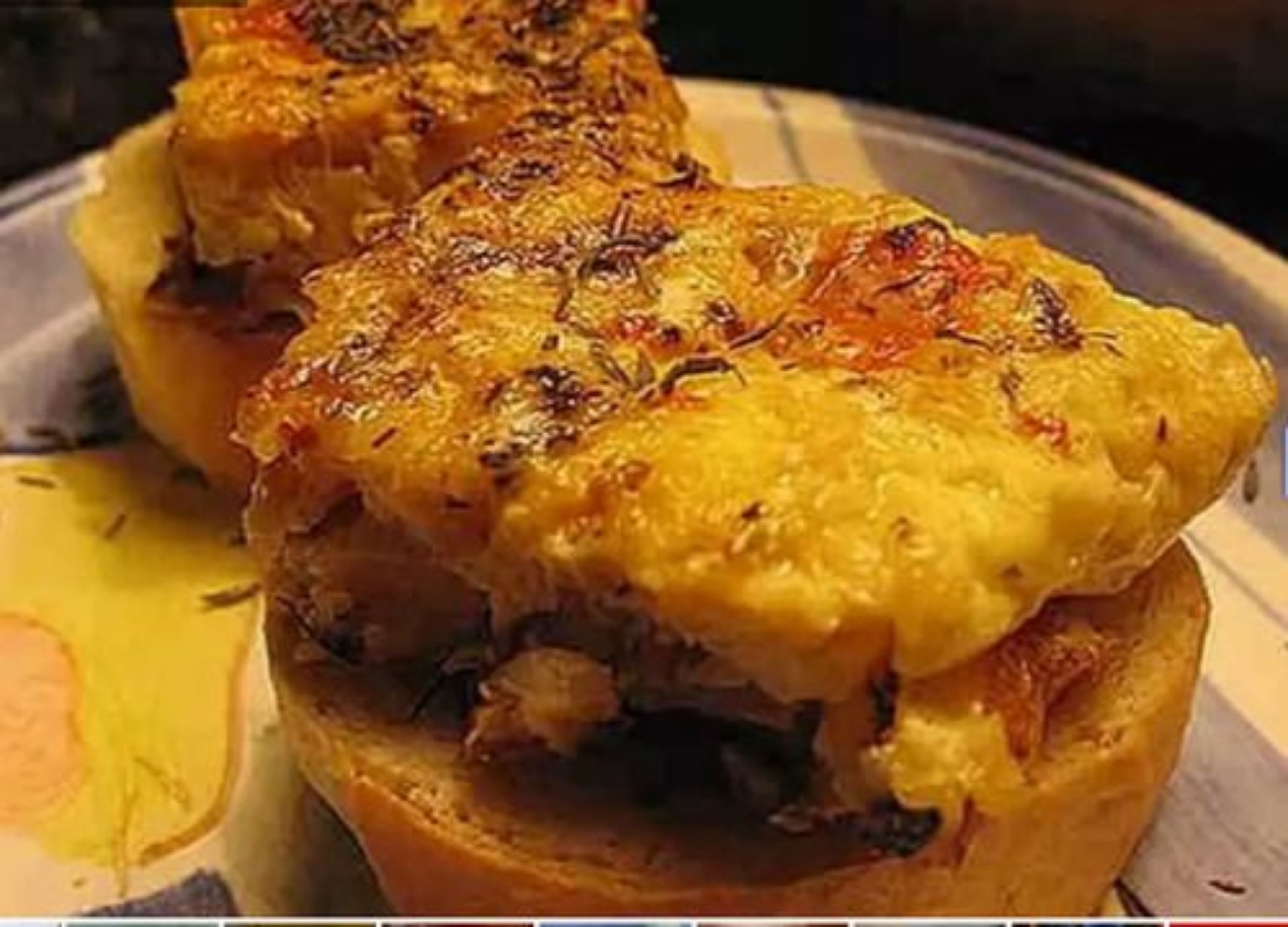 A sandwich with melted cheese and herbs on a plate.