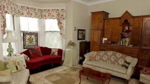 Un salon avec un canapé rouge, un canapé beige et un meuble en bois.