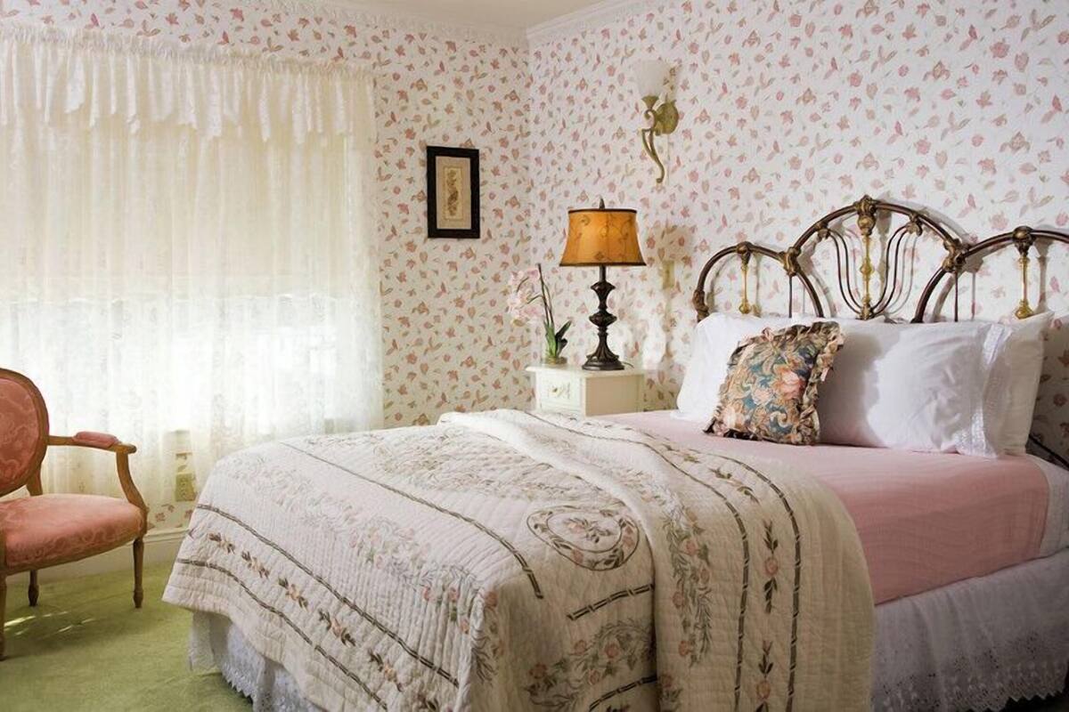 A bedroom with a bed, a chair, a nightstand, and a lamp.