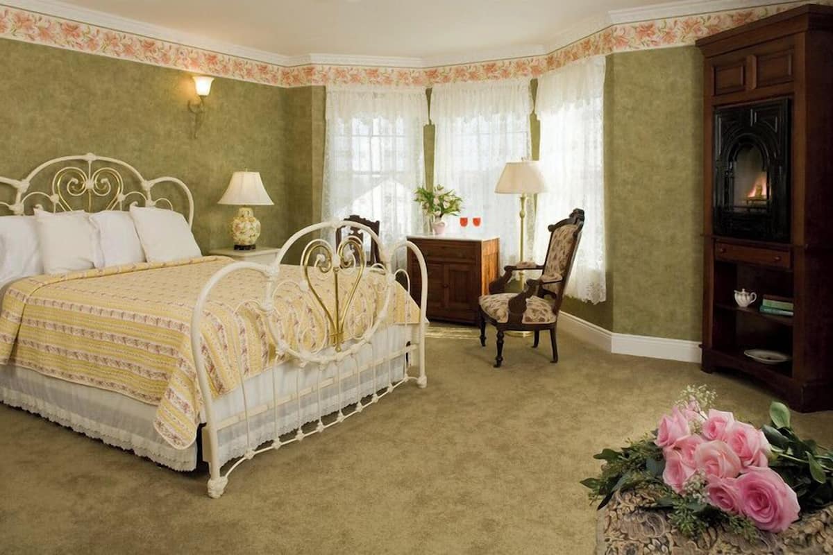 A bedroom with a bed, a chair, a desk, and a cabinet.
